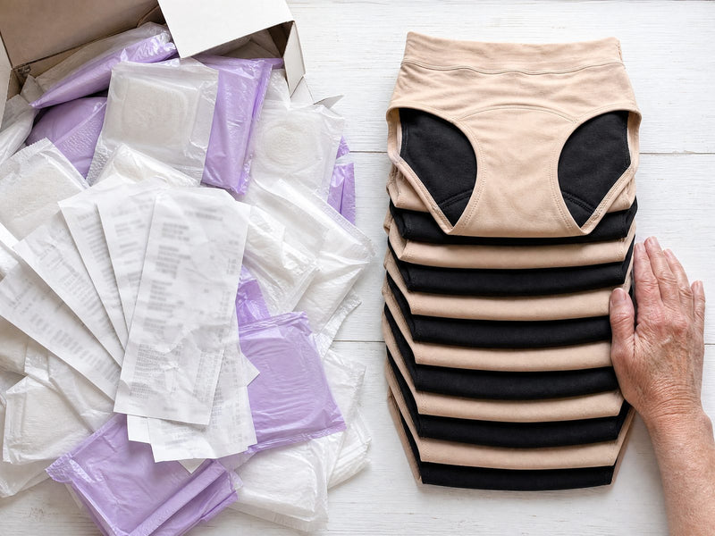A pile of disposable pads and store receipts next to a neat stack of folded beige and black Haven underwear