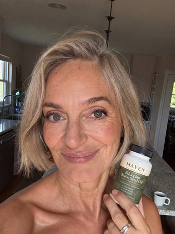 Customer holding Haven Ethiopian Black Seed Oil in her kitchen