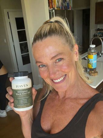 Customer holding Haven Black Seed Oil in her kitchen